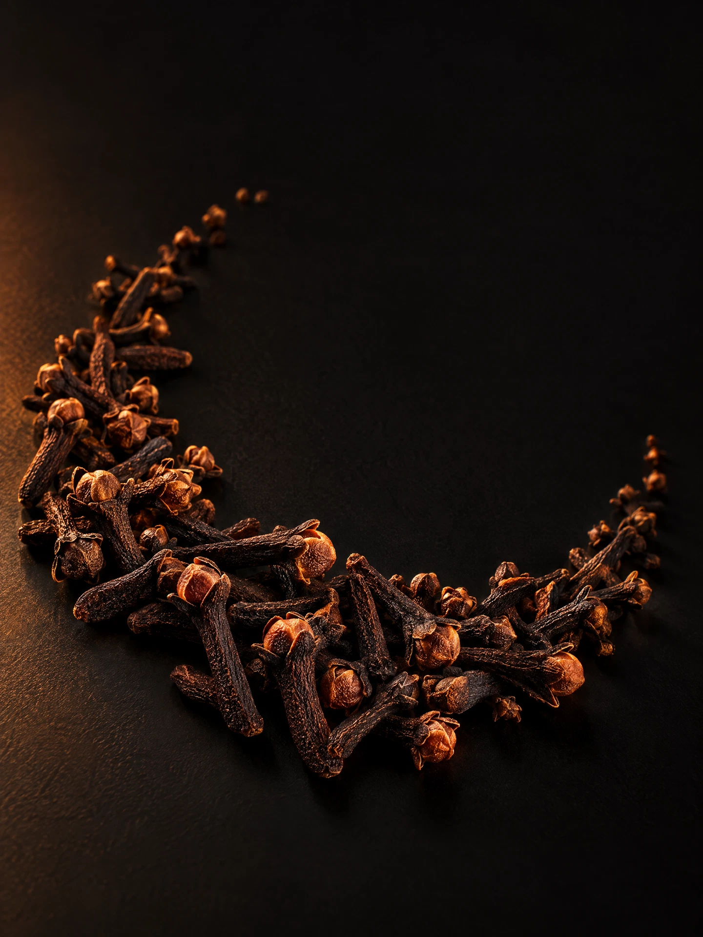 Whole cloves arranged on dark stone